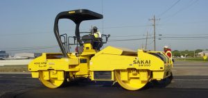 Sakai SW990 high frequency vibratory double drum asphalt roller operating on a paving jobsite.