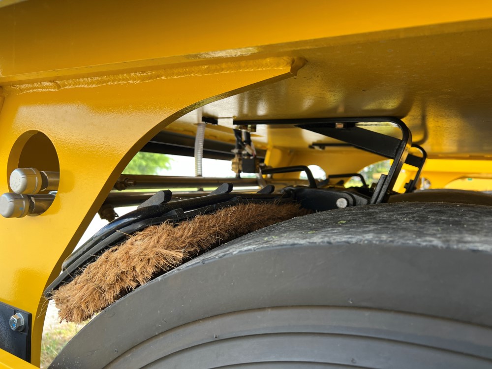 Side of the optional front cocoa mats on a SAKAI GW754 vibratory pneumatic tire roller or PTR. Cocoa mats help spread water on the tires to prevent asphalt pickup.
