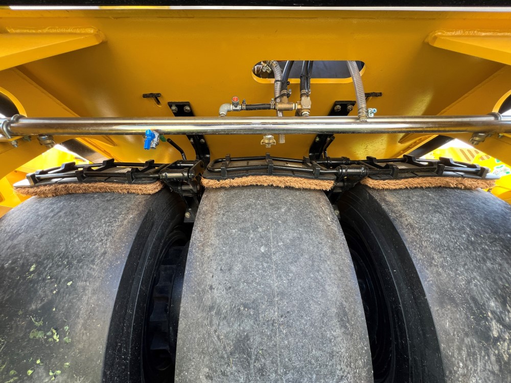 Front view of the optional front cocoa mats on a SAKAI GW754 vibratory pneumatic tire roller or PTR. Cocoa mats help spread water on the tires to prevent asphalt pickup.