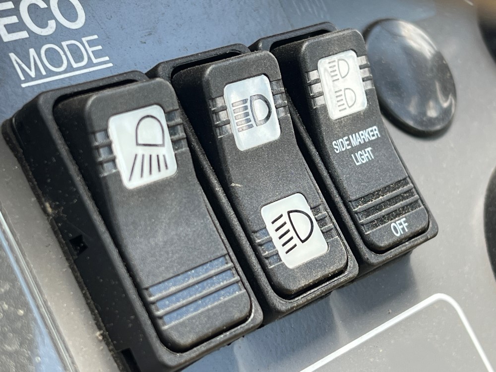 Close up of lighting switches on a SAKAI SW654 asphalt roller operator dash console.