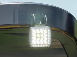 Close up of illuminated LED work light assembly on the ROPS of a SAKAI SW654 vibratory asphalt roller.