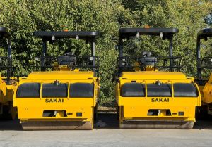 Front view of two Sakai double drum highway class asphalt rollers comparing the regular height ROPS roll over bar vs the optional low profile ROPS.