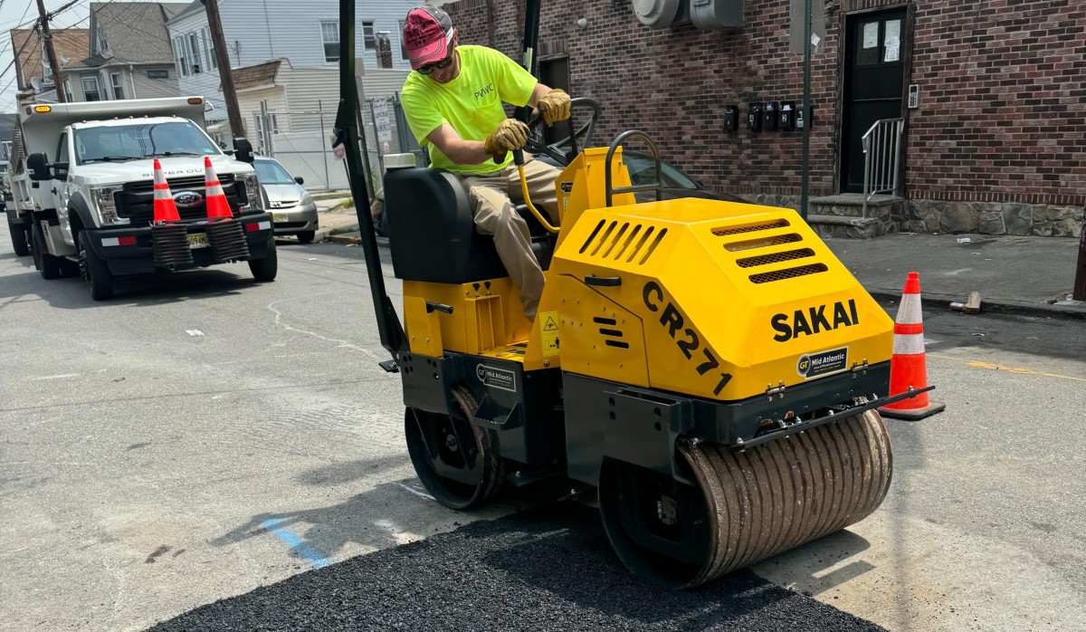 A 1.5 ton Sakai CR271 vibratory double drum 35.5" asphalt roller compacts a utility patch for a municipal water authority.