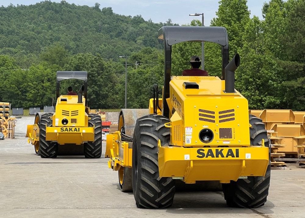 Two newly manufactured Sakai SV544 soil compactors leave the factory in adairsville GA as seen from the rear width tractor style tires.