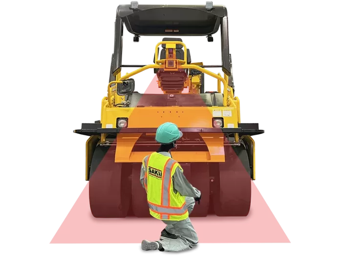 Rear view of a SAKAI GW754G vibratory pneumatic tire roller or PTR equipped with the automatic emergency braking system called Guardman with a paving worker behind the machine within a detection beam.